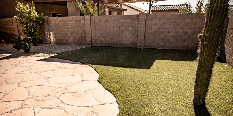 A backyard scene with a green grass area and a new patio space for relaxation and enjoyment.